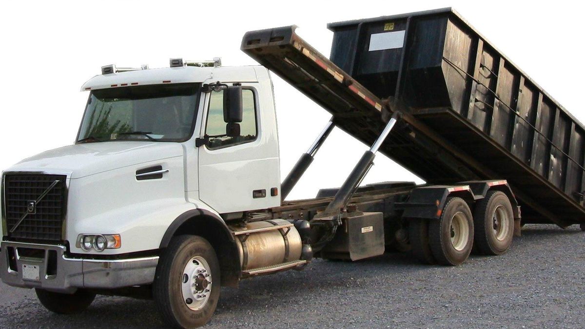 Roll-off truck with a large debris dumpster for hauling junk away