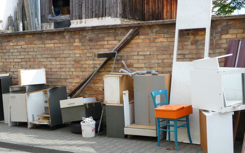 Old cabinets, shelving and a chair set out on the curb for junk removal